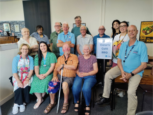Carers cafe participants and volunteers gather round for a group photograph