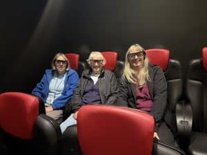 3 ladies sit in the 4D cinema with their 3D glasses on