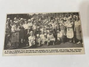 A newspaper clipping showing a black and white photograph of residents celebrating VE Day in Welbeck Road East Barnet.