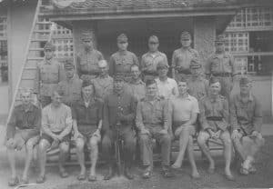In this image, a group of Japanese Prisoners of War sit with their former guard in a group photograph.