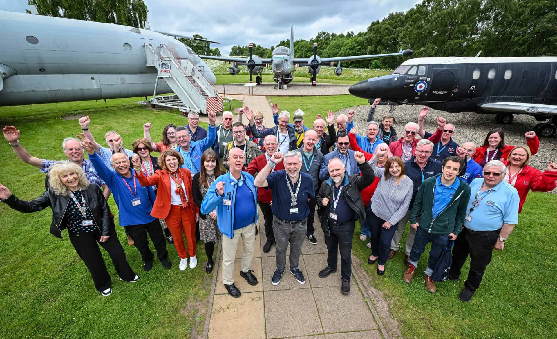 Group of volunteers all looking at the camera standing in front of the Nimrod at Cosford
