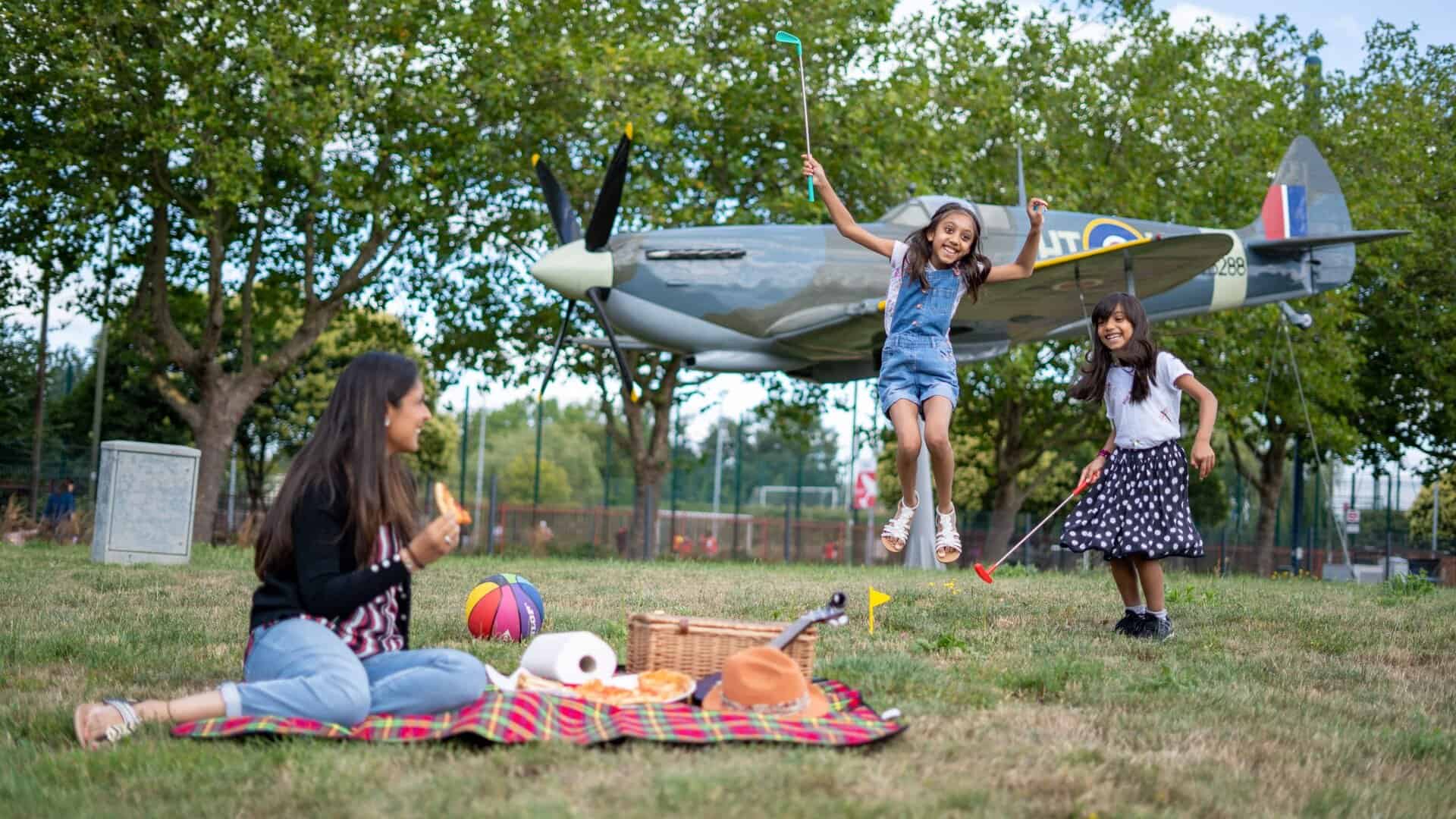 Family outside having a picnic with a spitfire in the background