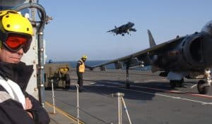 On HMS Invincible, Sean Bell stands watching the Harriers take off. Image Credit Christine Wood