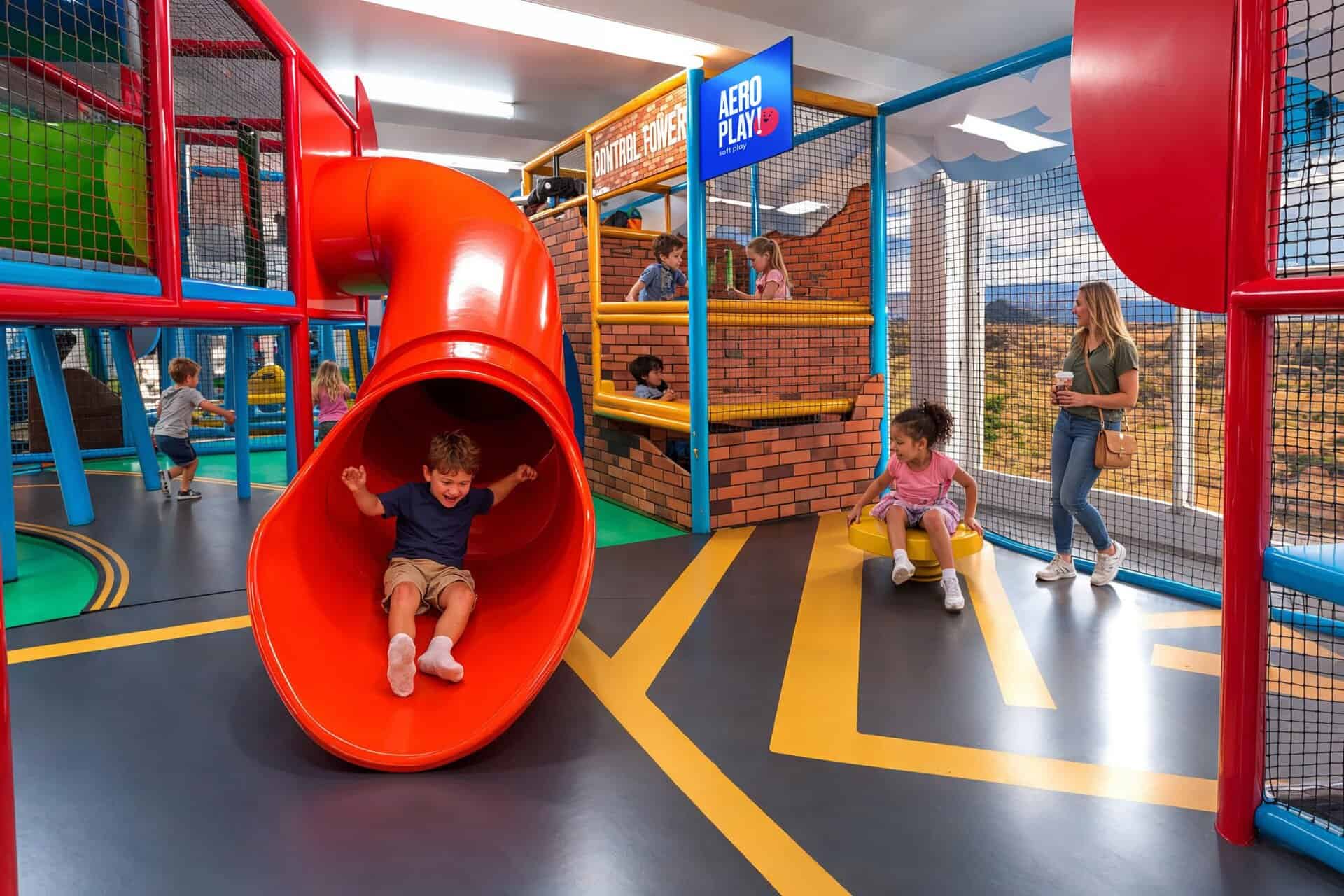 Kids sliding down aeroplay slide
