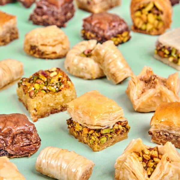 Delicious assorted baklava and nut-filled pastries displayed on a light green background.