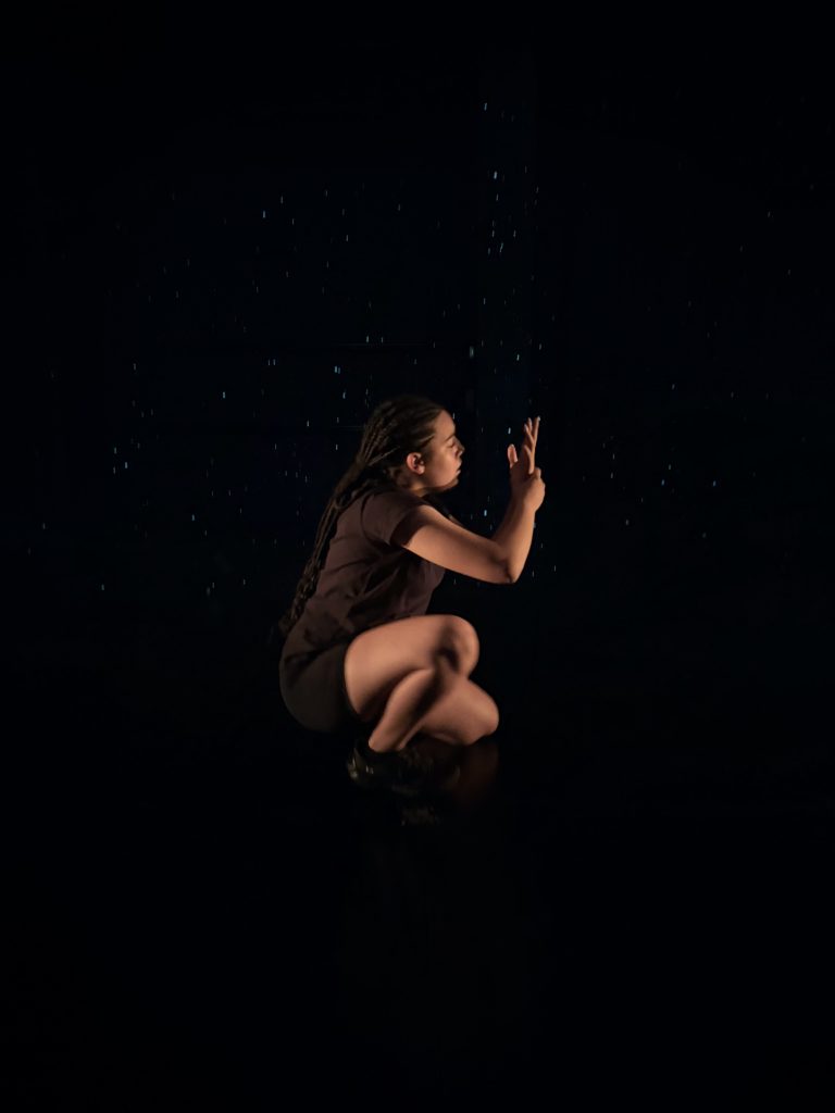 A person kneeling in the dark.