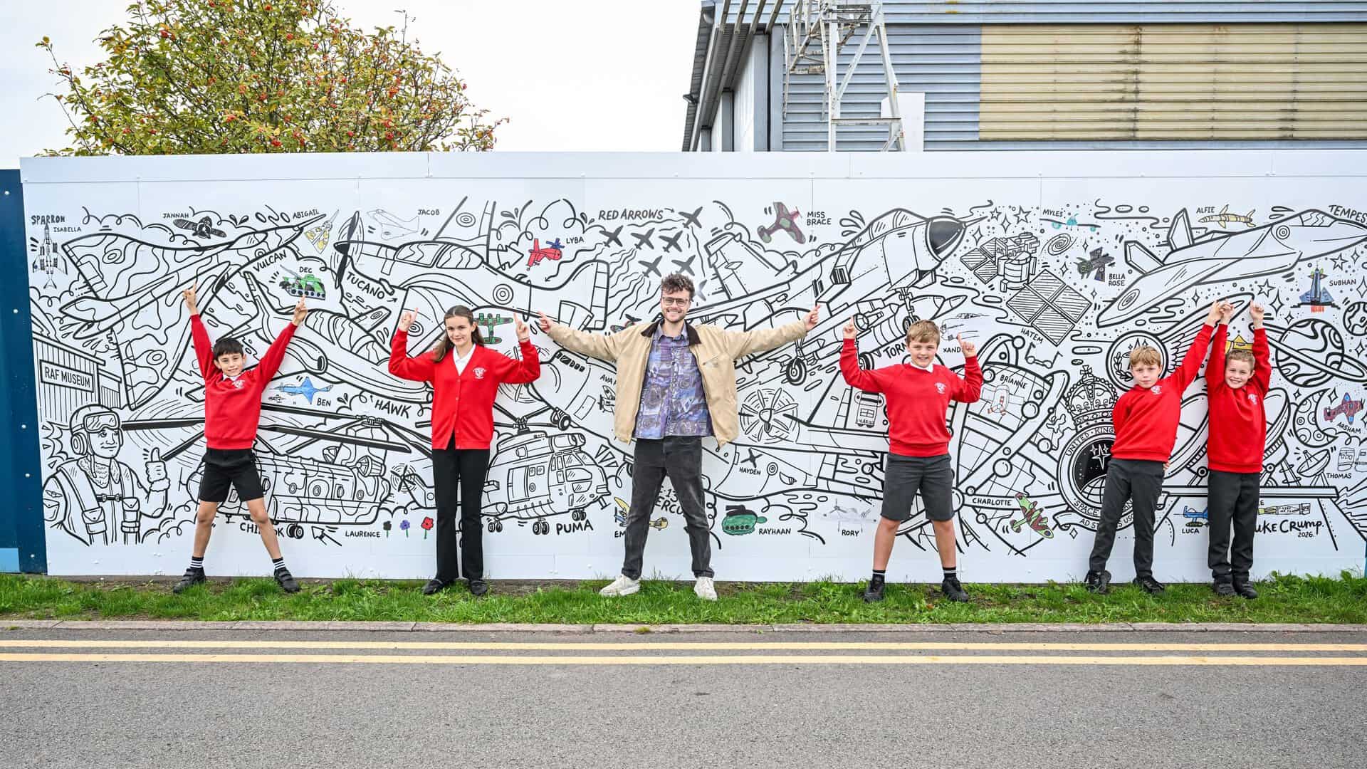 Artist Luke Crump and students from St Mary's Primary School in Albrighton view the Hangar 1 Exhibition mural at RAF Museum Midlands
