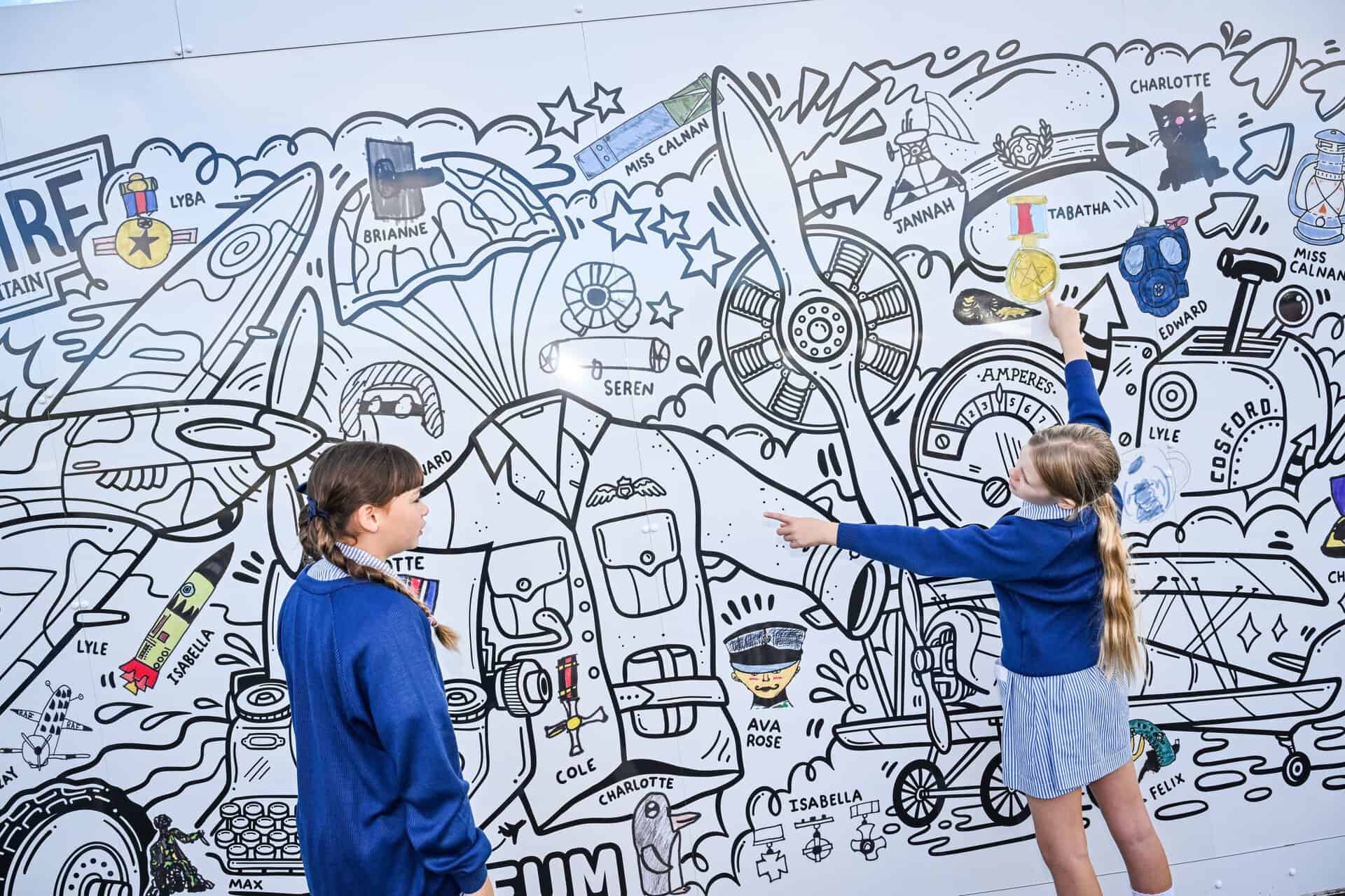 Students from Castle House Primary School in Telford view their artwork within the mural at RAF Museum Midlands