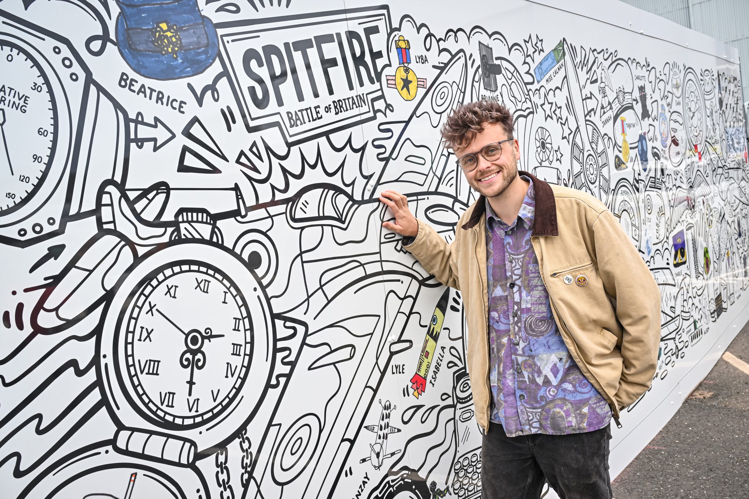 Artist Luke Crump with the Collections Hub mural at RAF Museum Midlands