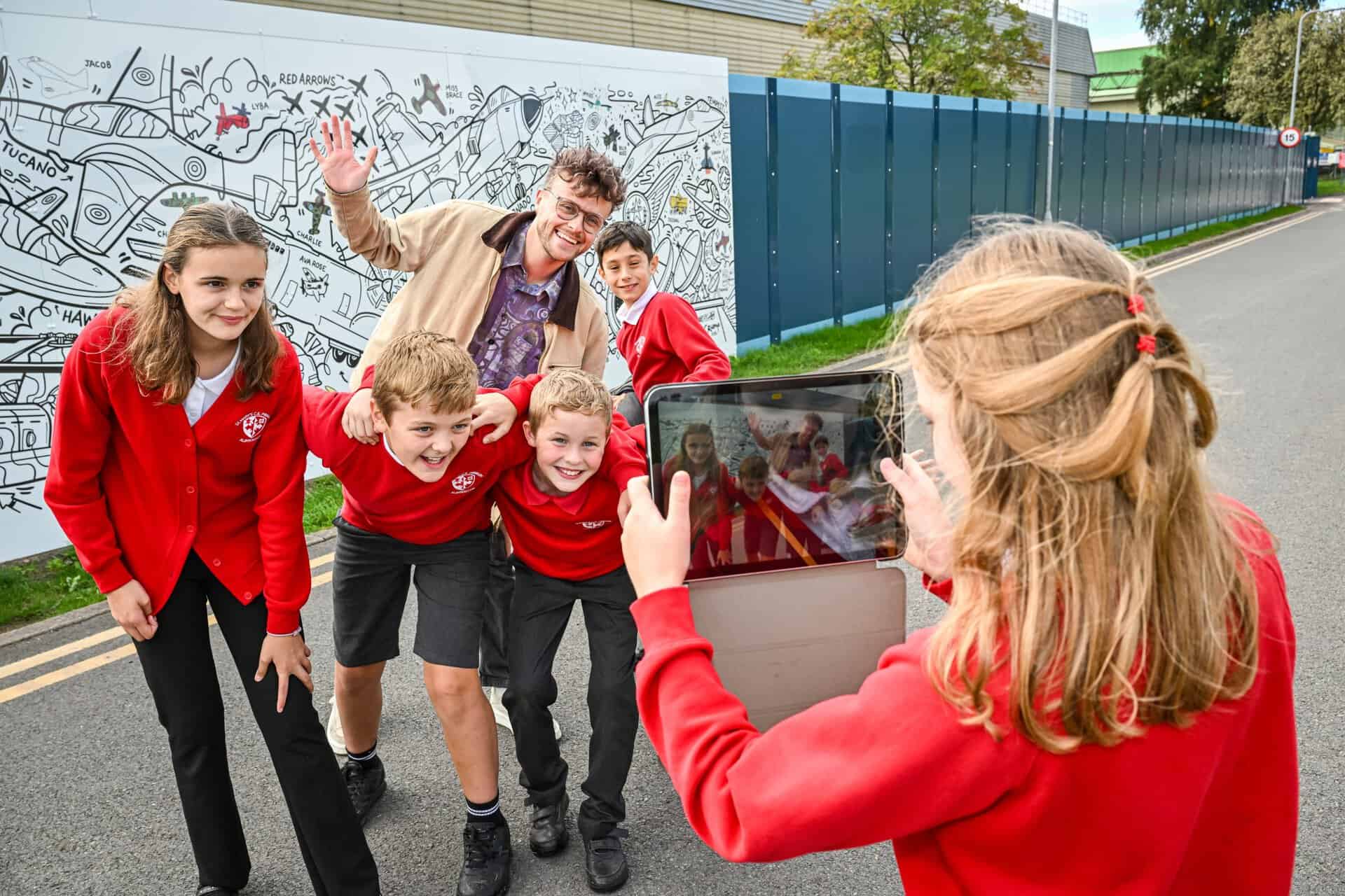 Artist Luke Crump and students from St Mary's Primary School in Albrighton view the Hangar 1 Exhibition mural at RAF Museum Midlands