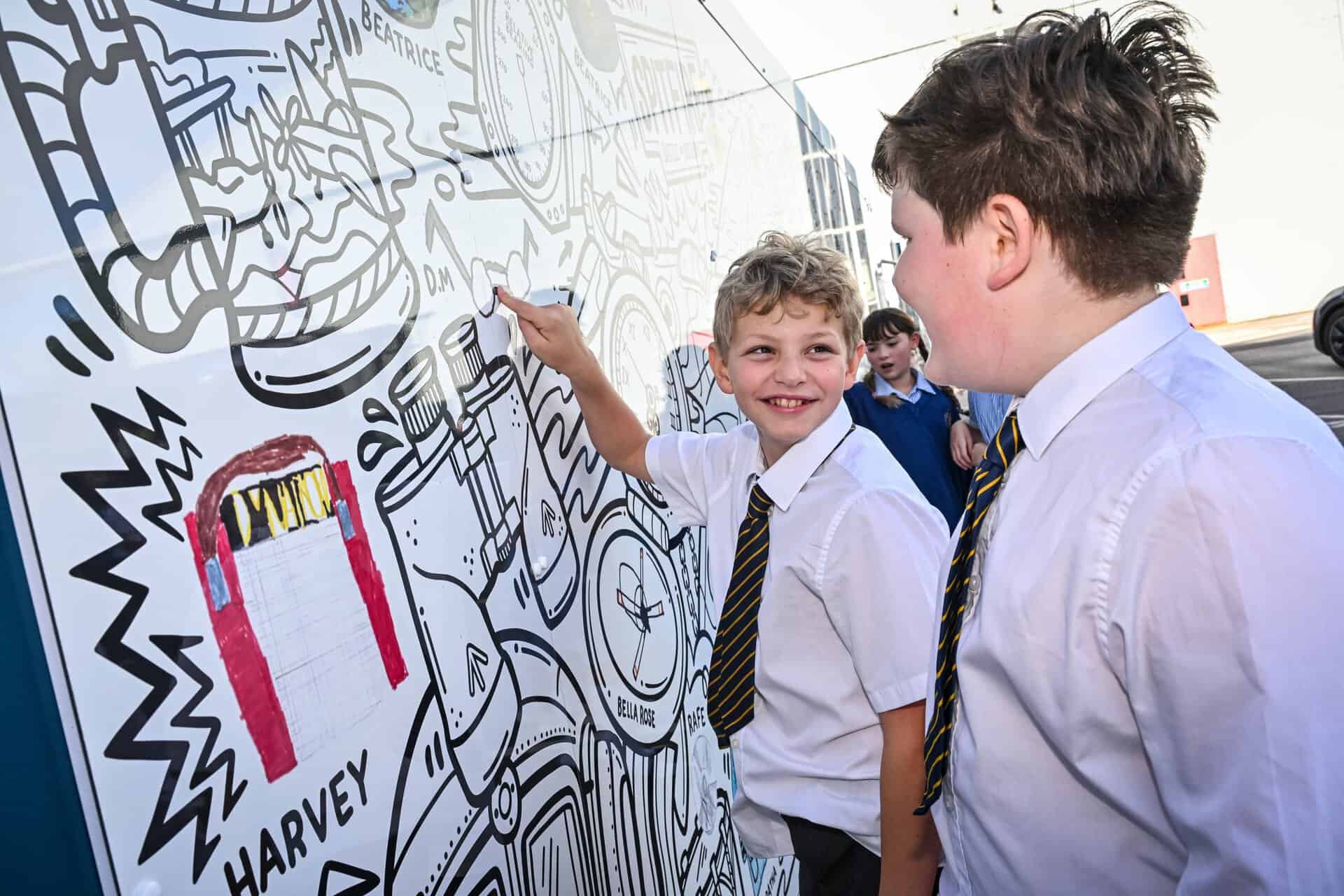 Students from Castle House Primary School in Telford view their artwork within the mural at RAF Museum Midlands