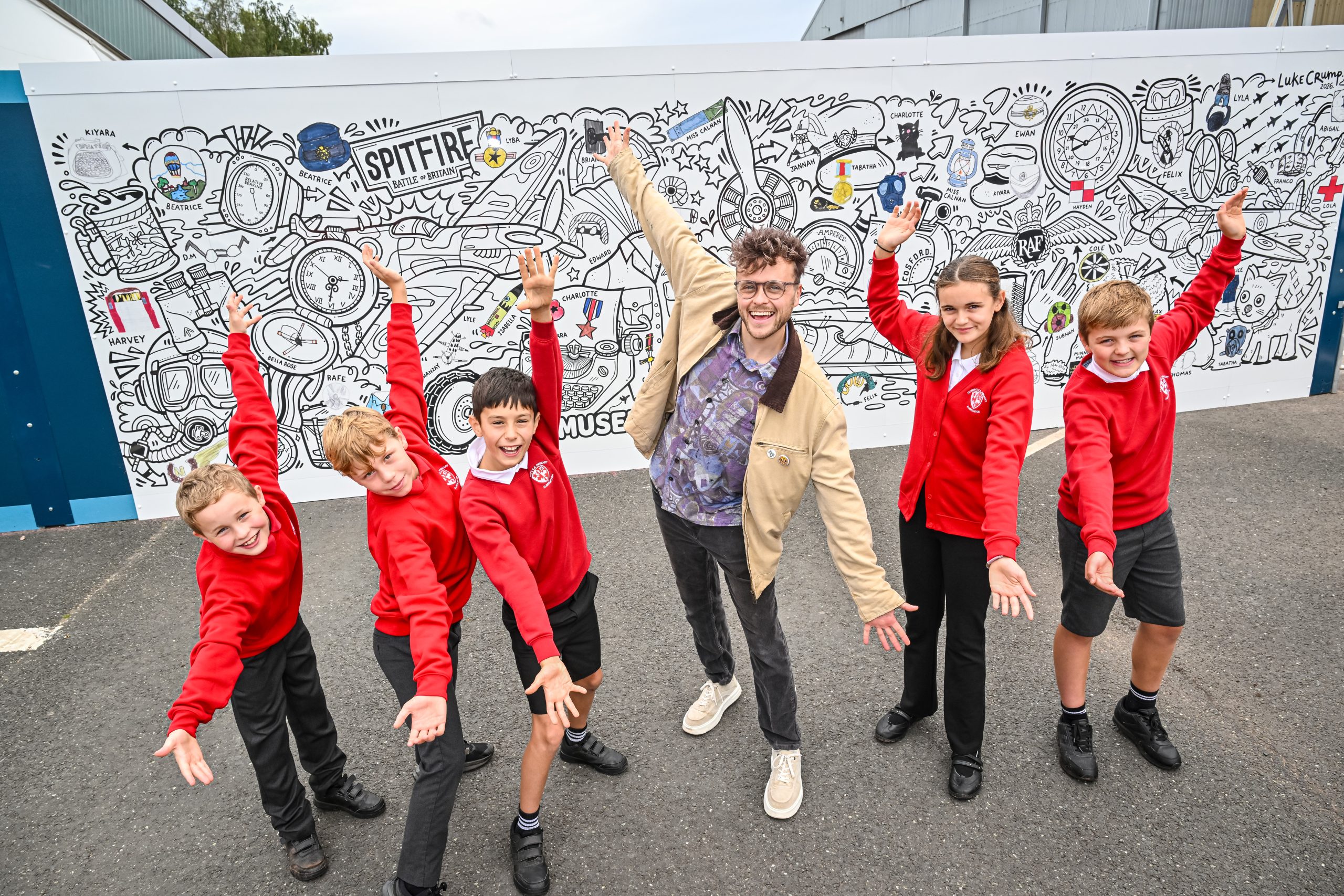 Artist Luke Crump and students from St Mary's Primary School in Albrighton view the Collections Hub mural at RAF Museum Midlands