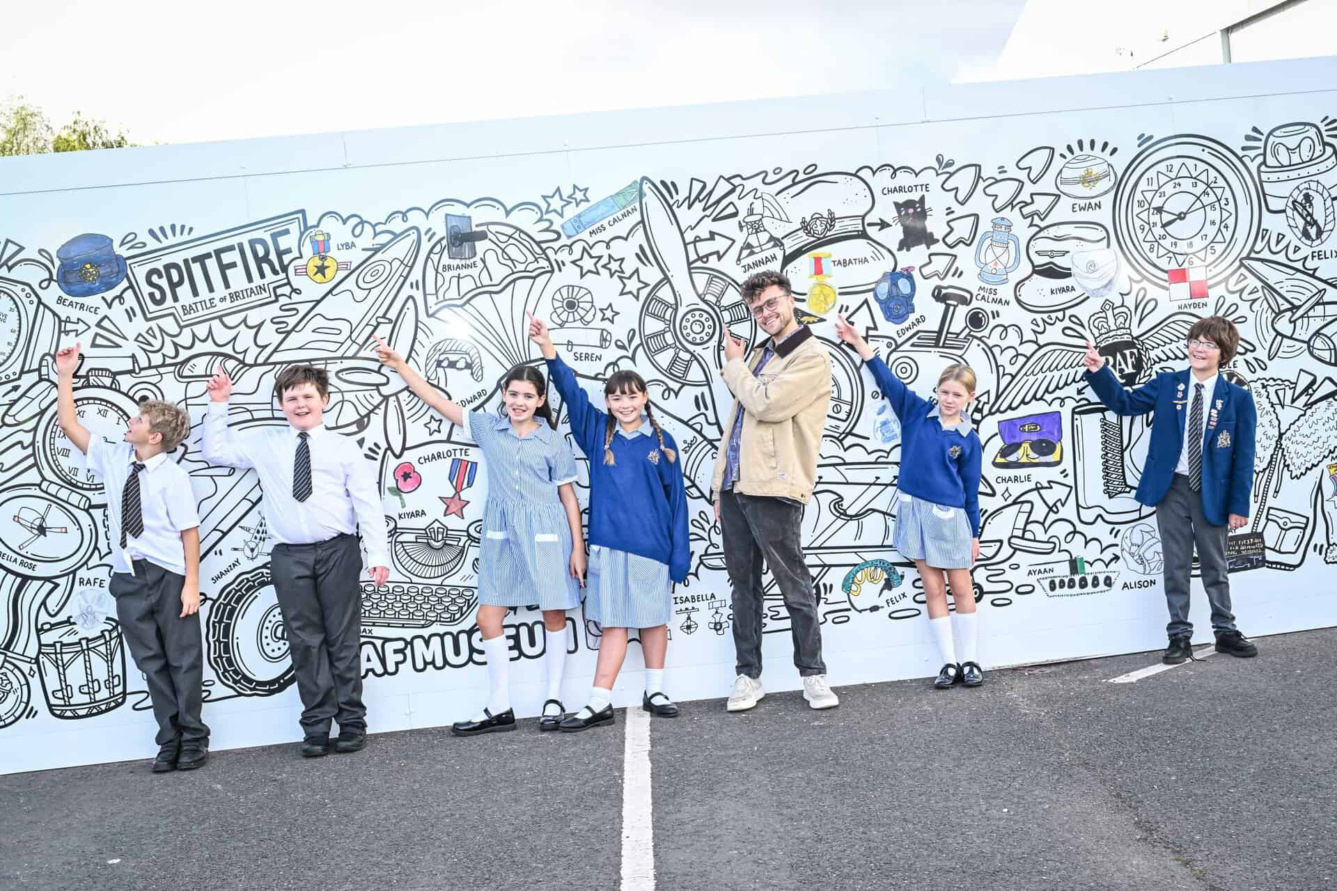 Artist Luke Crump and student from Castle House Primary School in Telford view the Collections Hub mural at RAF Museum Midlands